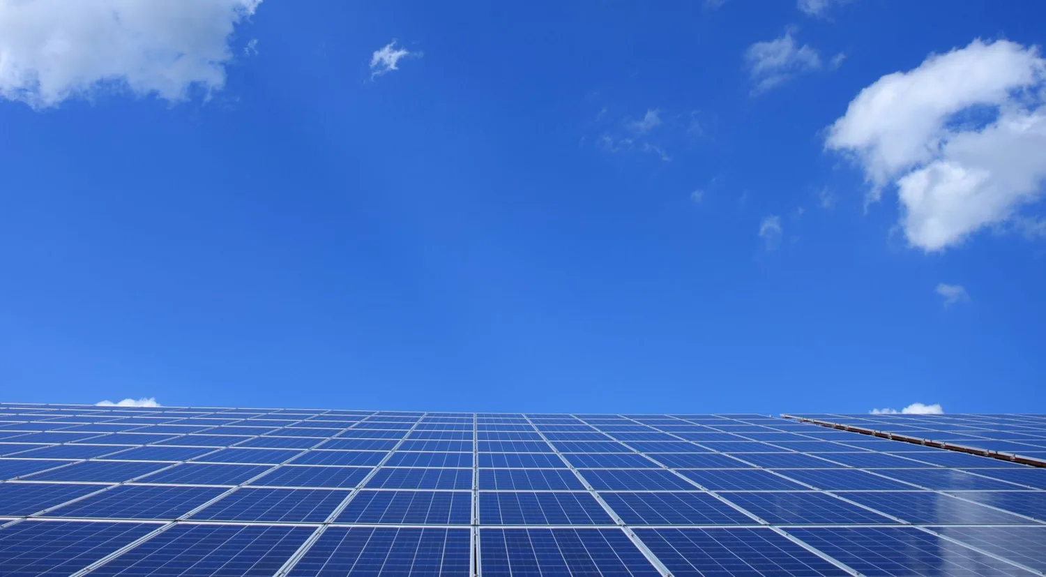 Blue solar panels beneath a bright sky